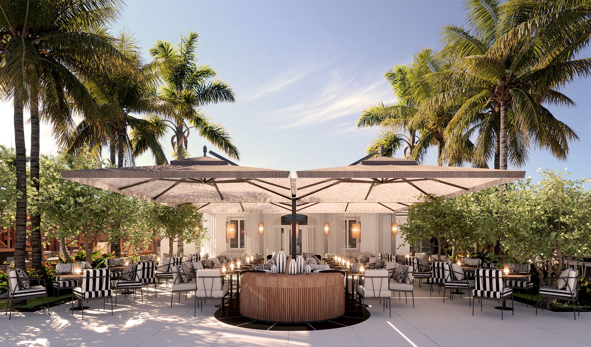 Outdoor dining area with umbrellas and seating, surrounded by palm trees and greenery, in a spacious and sunny setting.