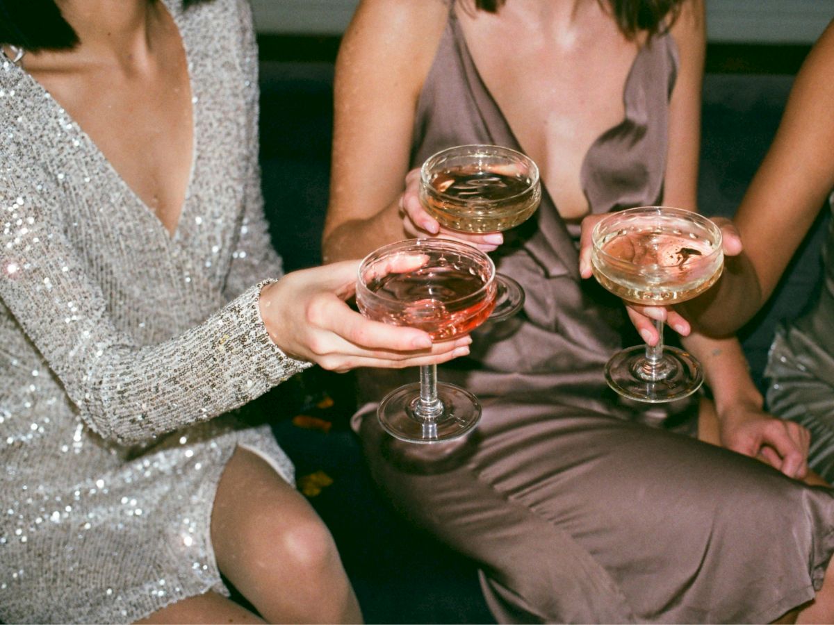 People in elegant dresses holding champagne glasses, toasting in a celebratory setting.