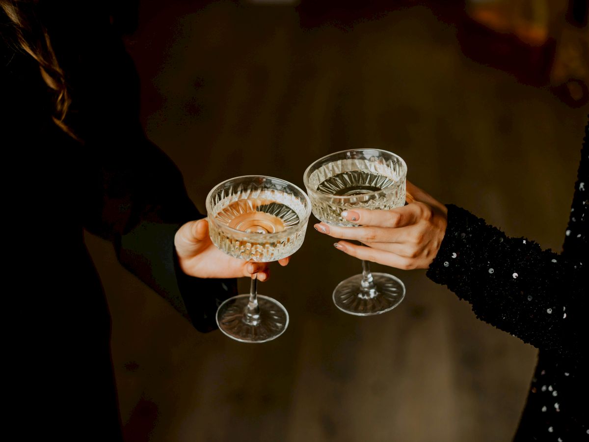 Two people clinking elegant glasses filled with champagne, celebrating or sharing a toast.